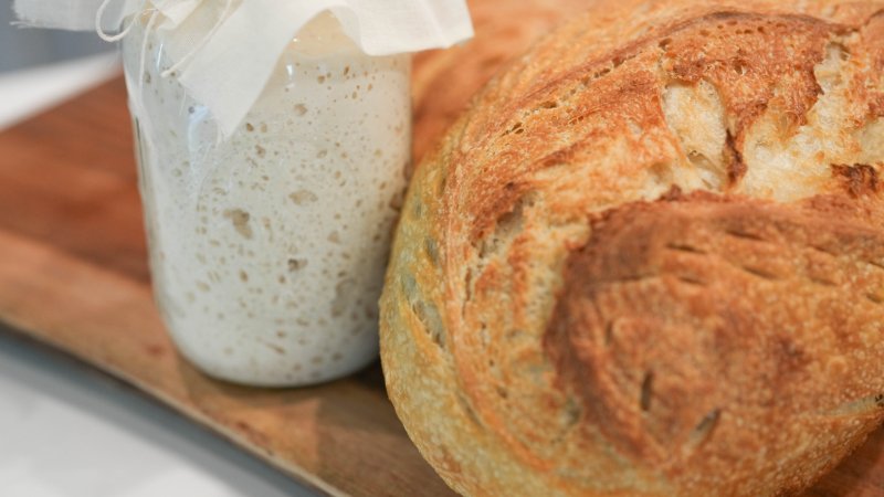 Long scored loaves standing upright in a paper-lined bakery basket.